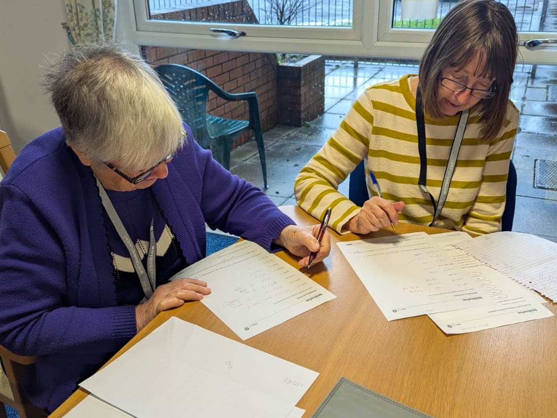 Learners Anita Hanney and Ann Williams with Maths exercise papers.